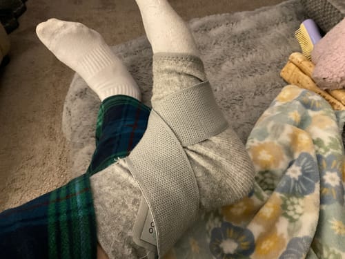 Reviewer wearing the grey Premium Bamboo Ankle Support with its adjustable strap wrapped around their ankle over a sock.