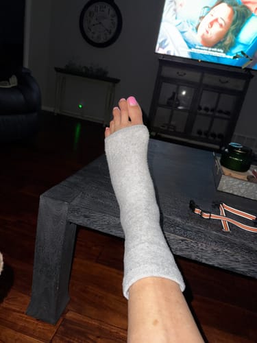 Reviewer relaxing with their foot up, wearing the grey Anti-Fatigue Bamboo Footsleeves.