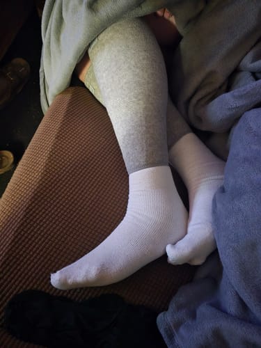 image 2 out of 2: A customer wearing the white Anti-Fatigue Bamboo Footsleeves while resting their feet.