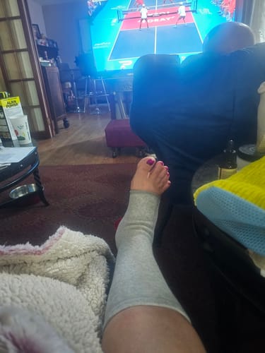 Reviewer relaxing with a grey anti-fatigue footsleeve worn as a calf sleeve on their leg.