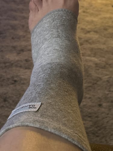 Close-up of a reviewer's ankle wearing the grey bamboo footsleeve.