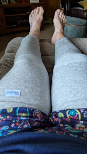 Customer's legs wearing grey Premium Bamboo Leg Sleeves while resting at home.