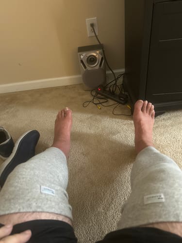 Customer's gray Premium Bamboo Leg Sleeves worn on legs while sitting on carpet.