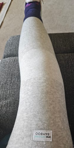Customer wearing the light grey Premium Bamboo Leg Sleeve on their leg while resting on a couch.