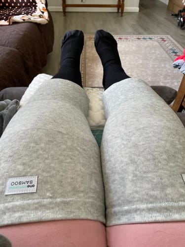 image 2 out of 2: Reviewer's legs propped up, showing the fit of the light gray Premium Bamboo Knee Sleeves on both knees.