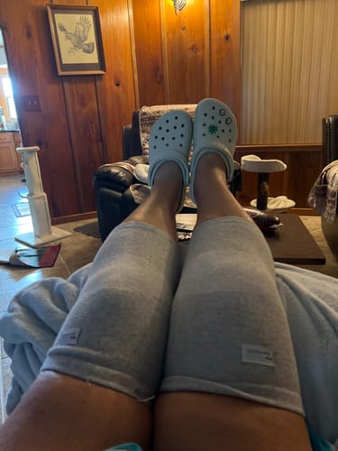 Customer relaxing with their legs propped up, wearing grey Premium Bamboo Knee Sleeves on both knees.