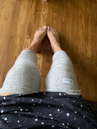 A reviewer's point-of-view shot wearing two grey Premium Bamboo Knee Sleeves on their legs against a wood floor.