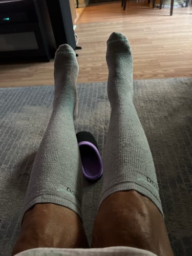Customer wearing grey Premium Bamboo Compression Socks with their legs propped up in a living room.