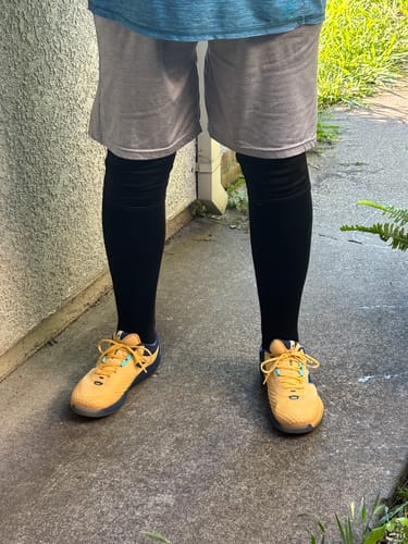 image 2 out of 3: Close-up of a customer wearing the black Premium Bamboo Compression Socks and yellow sneakers.
