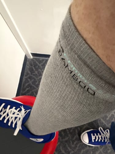 Customer wearing the grey Premium Bamboo Compression Socks up to their knee, with blue sneakers on.