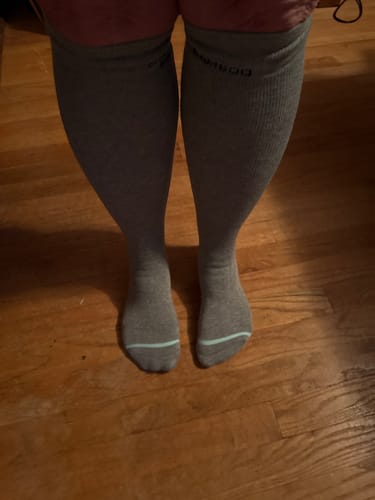 Customer standing while wearing the grey Premium Bamboo Compression Socks on a wood floor.