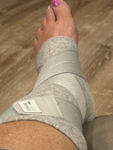 Customer's foot wearing the grey Premium Bamboo Ankle Support, showing the adjustable strap.