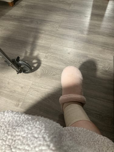 Customer wearing the tan Anti-Fatigue Bamboo Footsleeve on their ankle, with a slipper over their foot.