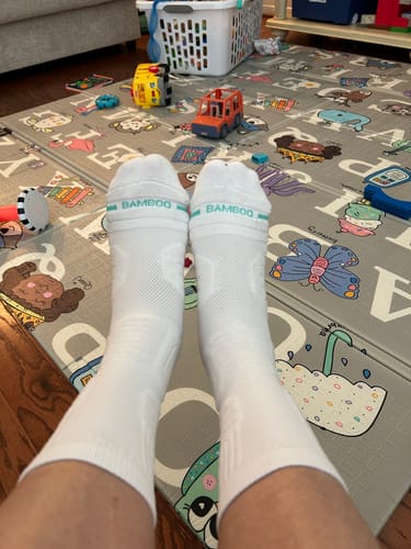 A customer's view of their feet wearing the white Anti-Fatigue Bamboo Footsleeves while relaxing at home.