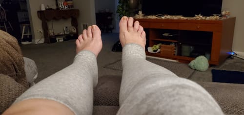 Customer's feet propped up while wearing the grey Anti-Fatigue Bamboo Footsleeves.