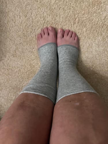 A customer's top-down view of their feet in the grey Bamboo Footsleeves on a carpet.