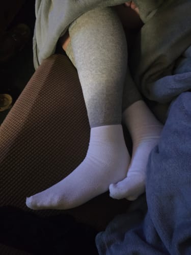 A customer wearing the white Anti-Fatigue Bamboo Footsleeves while resting their feet.
