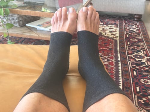 Customer relaxing with their feet up, wearing the black Anti-Fatigue Bamboo Footsleeves.