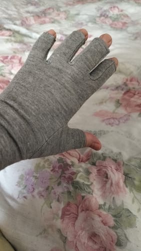 Reviewer shows their hand in a grey, open-fingertip Premium Onecompress™ Glove against a floral background.