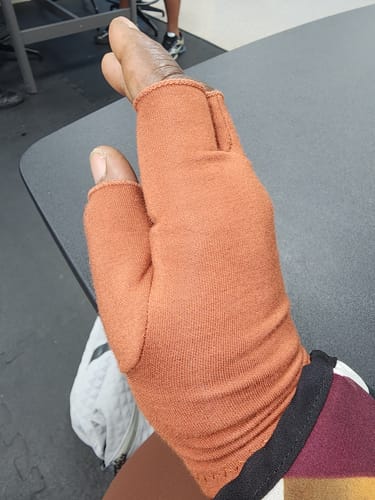 Customer's hand wearing the brownish-orange Premium Onecompress™ Glove, showing the open-finger design.