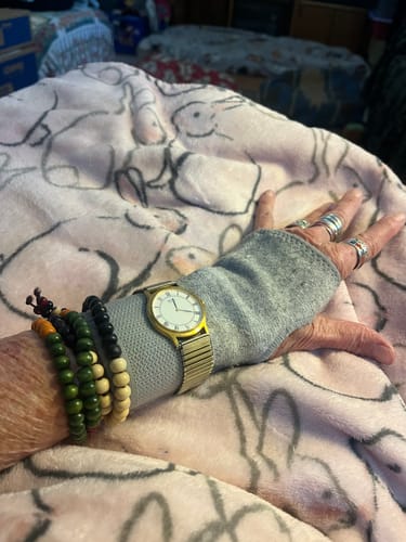 Customer's hand wearing the grey Onecompress™ Gloves under a watch and bracelets while resting.