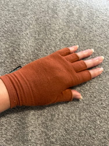 Reviewer wearing a brown Onecompress™ Glove, showing the open-fingertip design against a grey background.
