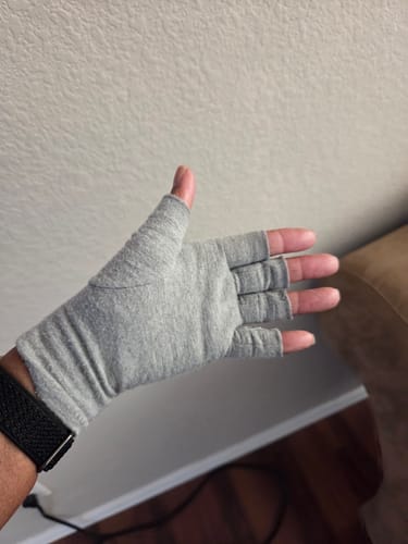 A reviewer's hand wearing a grey, fingerless Premium Onecompress™ Glove, showing the open-fingertip design.