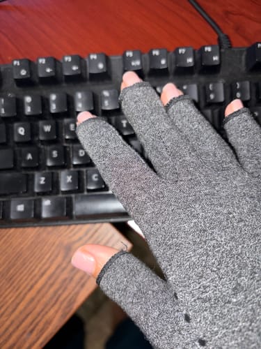 Customer wearing a grey Onecompress™ Glove with an open-finger design, resting their hand on a keyboard.