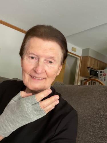A customer smiling while wearing the grey, open-finger Premium Onecompress™ Gloves.