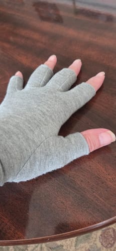 Customer's hand wearing the grey, open-fingertip Onecompress™ Gloves on a table.