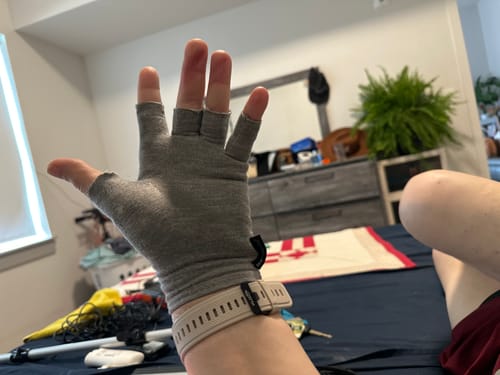 Customer's hand wearing a grey Onecompress™ Glove, showing the open-finger design indoors.