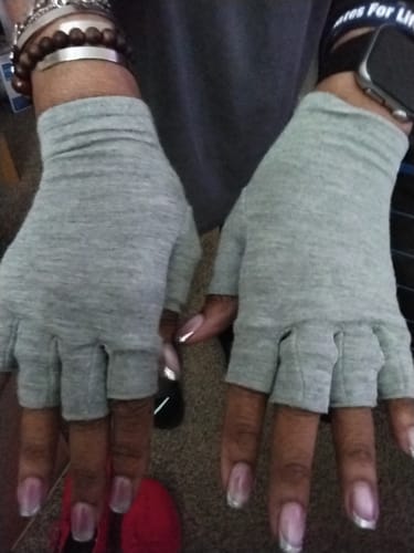 Reviewer wearing a pair of grey, open-fingered Premium Onecompress™ Gloves on both hands.