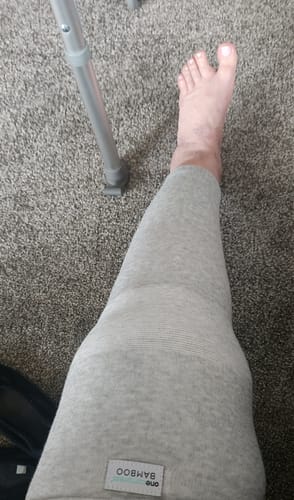 Reviewer wearing the grey Premium Bamboo Leg Sleeve on their leg for recovery, with a crutch visible nearby.