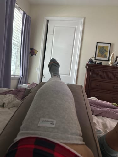 Reviewer resting with their leg elevated, wearing the grey Premium Bamboo Leg Sleeve for compression after surgery.