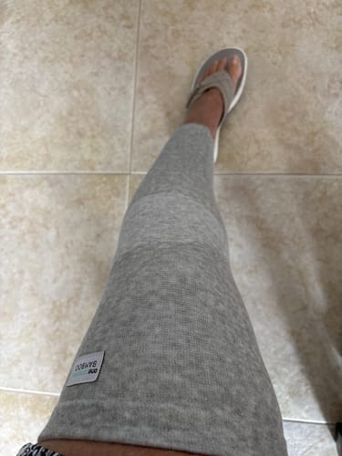 Customer's gray Bamboo Leg Sleeve worn on their lower leg while standing on tile flooring.