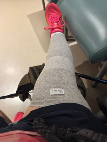 Reviewer sitting down, wearing the grey Premium Bamboo Leg Sleeve covering their entire leg from thigh to ankle.