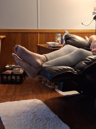 Customer relaxing in a chair while wearing the grey Premium Bamboo Leg Sleeves.