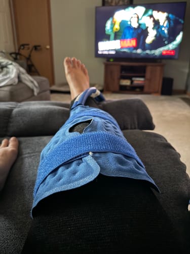 Customer's leg propped up, wearing the black Premium Bamboo Leg Sleeve with a blue pack over the knee.