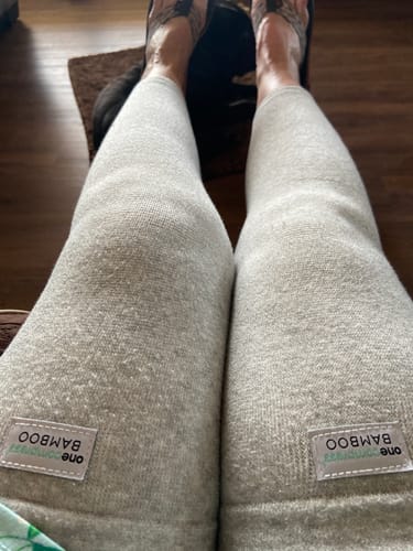 Reviewer resting while wearing a pair of light grey Premium Bamboo Leg Sleeves covering their full legs.