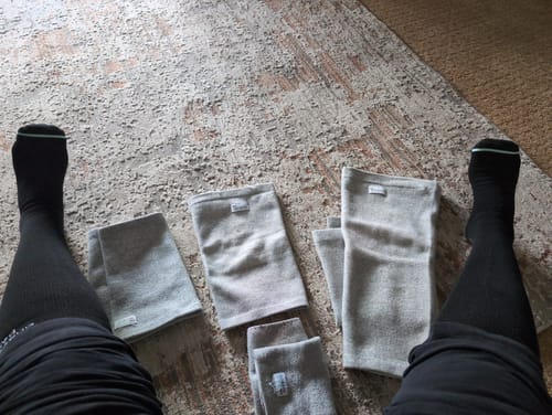 Reviewer's collection of gray Premium Bamboo Leg Sleeves in various sizes laid out on a rug.