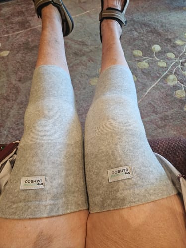 Reviewer sitting with their legs extended, wearing a pair of grey Premium Bamboo Knee Sleeves for support.
