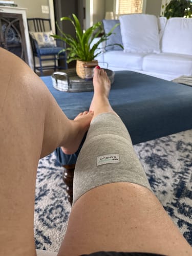 Customer wearing the grey Premium Bamboo Knee Sleeve on their leg while resting in their living room.