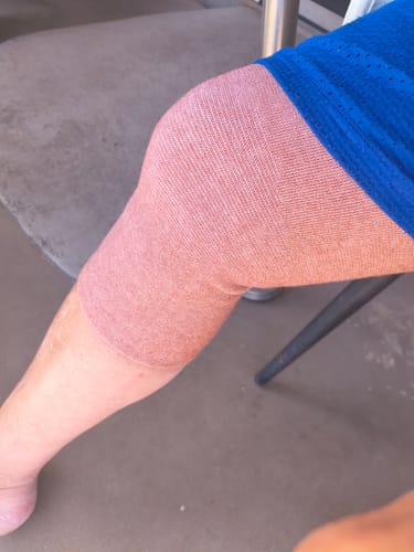 A customer's leg wearing the light brown Premium Bamboo Knee Sleeve, covering the knee from mid-thigh to upper calf.