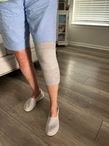 Customer wearing the grey Premium Bamboo Knee Sleeve on their leg while standing indoors.