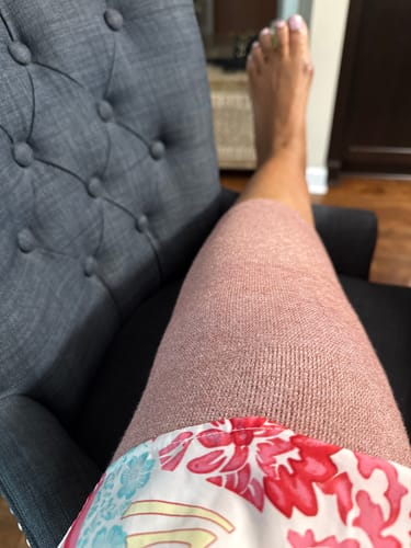 Reviewer resting in a chair while wearing the pink Premium Bamboo Knee Sleeve.