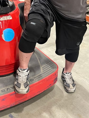 Customer wearing black Premium Bamboo Knee Sleeves on both knees at work.