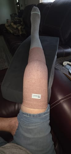 Customer resting with their leg propped up, wearing the Premium Bamboo Knee Sleeve over a sock.