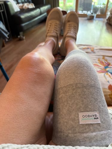 Reviewer resting with one leg in a grey Premium Bamboo Knee Sleeve and the other bare.
