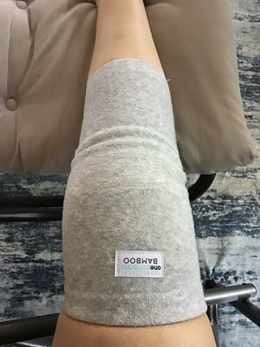 Customer wearing the light grey Premium Bamboo Knee Sleeve on their elevated leg, post-surgery.