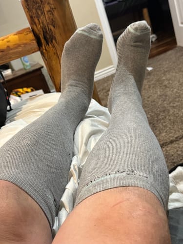 Reviewer wearing the grey, ribbed Premium Bamboo Compression Socks while resting their legs.